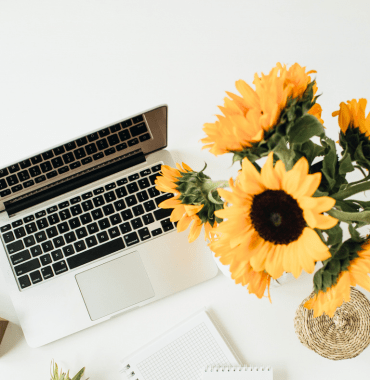 Sunflowers on white desk with laptop